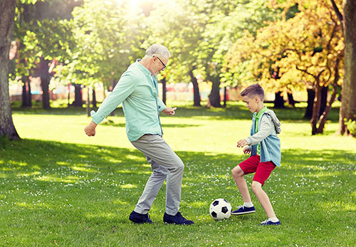 Senior spielt Fussball mit seinem Enkel